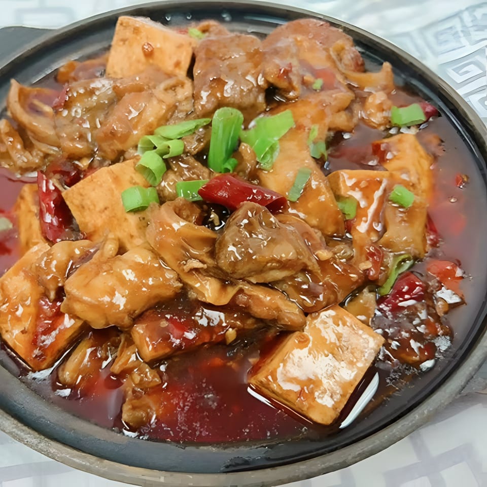 Peppercorns Kitchen's braised pork belly and tofu in a rich, spicy sauce, garnished with green onions.