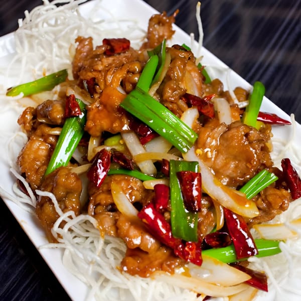 Peppercorns Kitchen's spicy Chinese dish with chicken, onions, green onions, and red chili peppers.