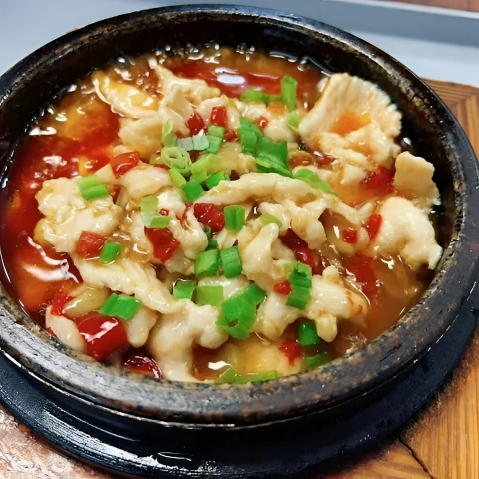 Peppercorns Kitchen's Chinese dish with white meat, red peppers, and green onions in a dark bowl.